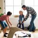 children helping a dad lifting carpet to clean hard wood floor in a living room